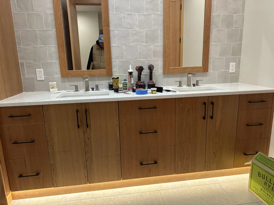 Wood double vanity with black pulls and under-cabinet toe-kick lighting