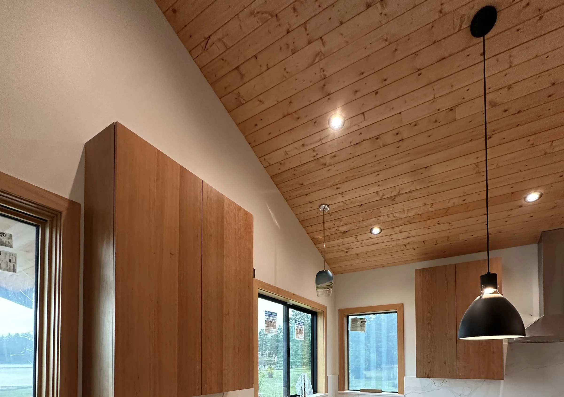 Kitchen with wood slab-door cabinets under a vaulted plank ceiling