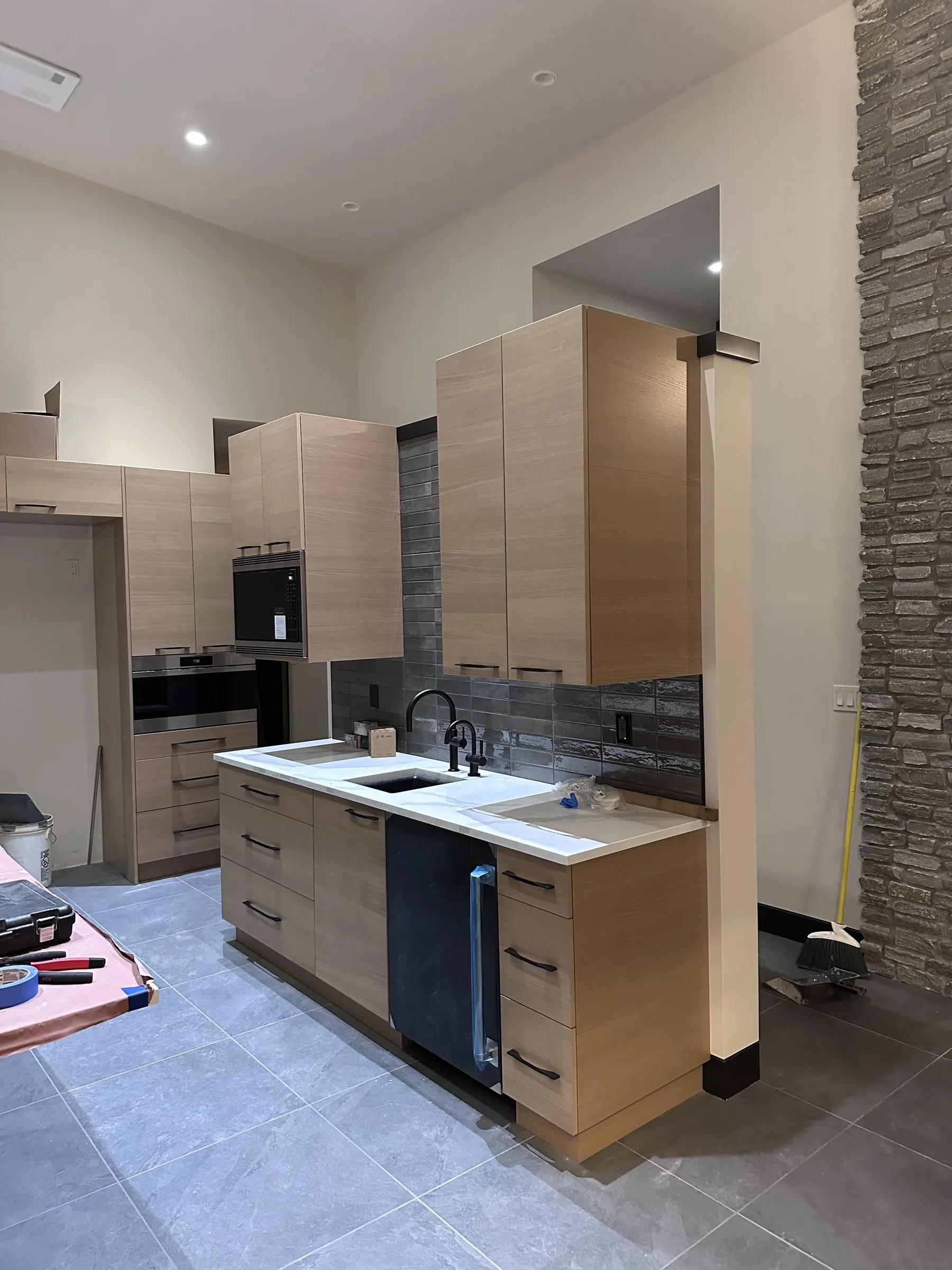 Light oak slab-door kitchen cabinets with black pulls