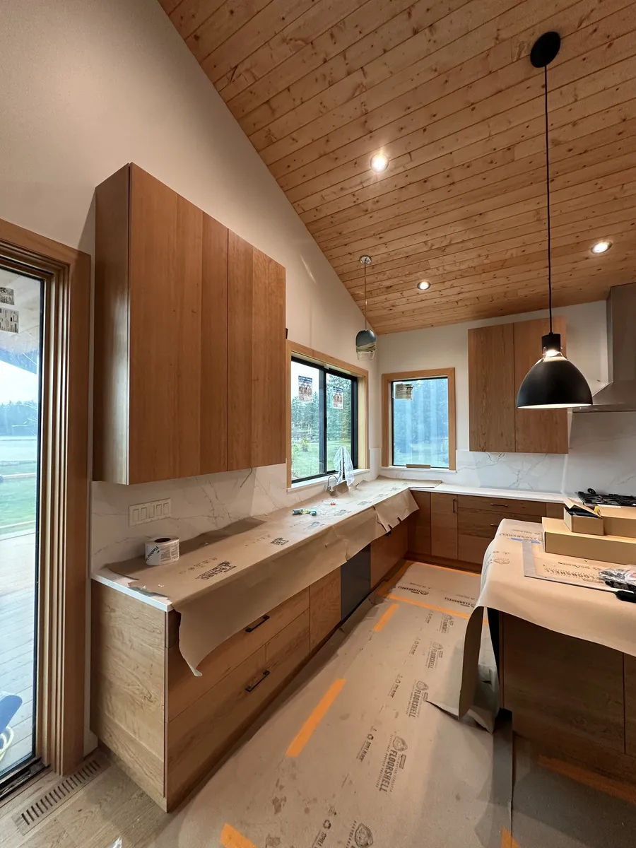 Kitchen with wood slab-door cabinets under a vaulted plank ceiling